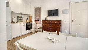 Eine moderne Küche mit weißen Schränken, einem Holztisch und einem flachbildfernseher an der Wand.