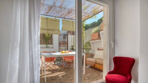 Ein Zimmer mit einer Schiebetür zum Außenbereich, der einen Tisch und Stühle sowie einen roten Sessel bietet.