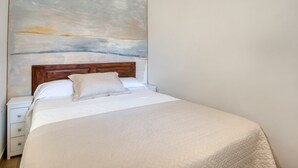 Ein Schlafzimmer mit Bett, Nachttisch, Holz-Kopfteil und einem großen abstrakten Gemälde an der Wand.