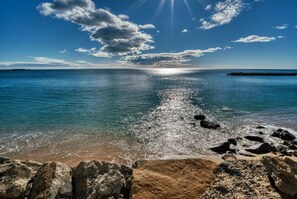 A beach with clear water, rocks, and a distant shoreline.