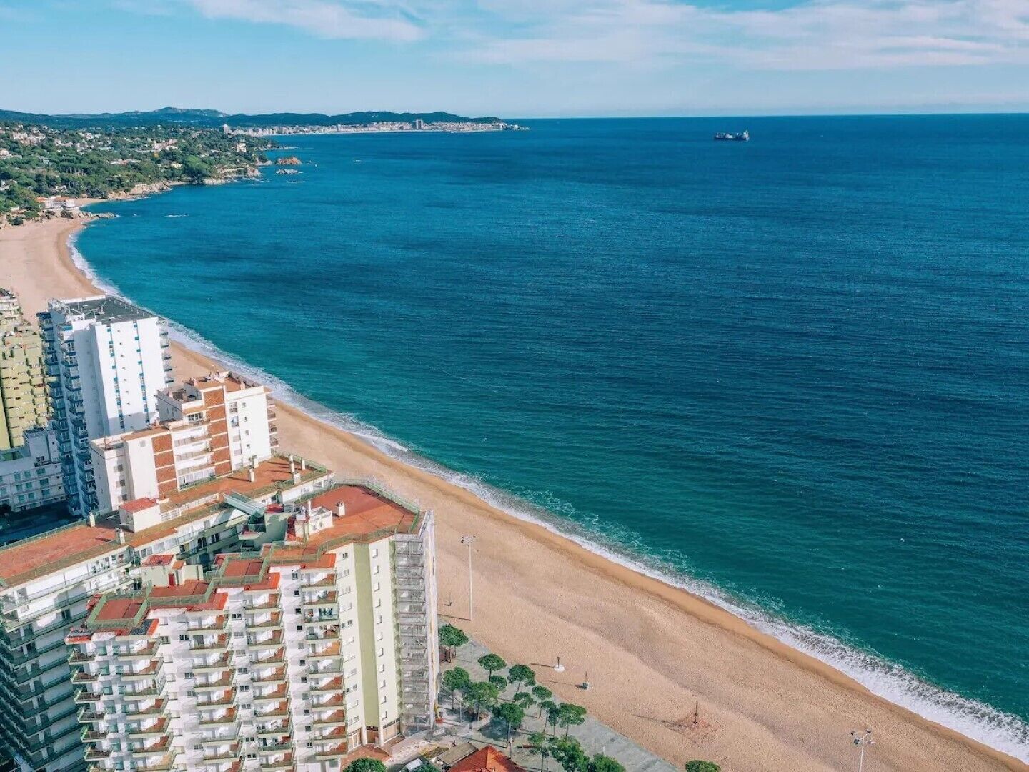Paisagem costeira com praia, edifícios altos e vista clara do mar.