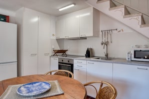A kitchen with white cabinets, a stove, a microwave, and a dining area with a table and chairs.