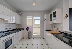A modern kitchen with white cabinets, a stainless steel sink, and a tiled floor.
