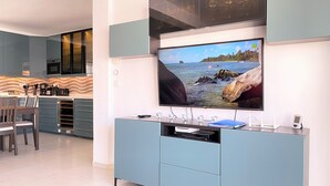 A modern kitchen with a built-in TV, a dining area, and a view of the sea. - Apartamento La Torna by Casasol (Nerja)
