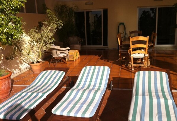 A sunlit patio with two lounge chairs, a wicker chair, and a potted plant. - Apartment "Boulevard 305" with Sea View, Pool, Wi-Fi, Balcony, Terrace & Garden (Estepona)