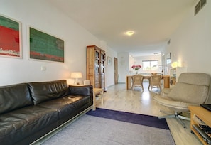 A living room with a leather sofa, a coffee table, a dining area with wicker chairs, and a TV stand. - Apartment "Boulevard 305" with Sea View, Pool, Wi-Fi, Balcony, Terrace & Garden (Estepona)