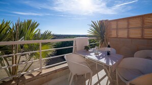 A balcony with a table and chairs, overlooking a landscape with palm trees and a clear sky. - Holiday Home "Casa Minuni" with Sea View, Terrace, Balcony, A/C & Wi-Fi (Almería)
