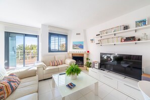 Un salon moderne comprenant un canapé, une table basse, un téléviseur, une cheminée et des étagères.