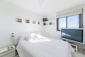 Une chambre à coucher avec un lit, une télévision, une table de chevet et des œuvres d’art accrochées au mur.
