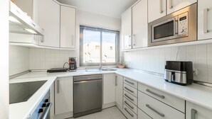 A modern kitchen with white cabinetry, a built-in microwave, a dishwasher, and a window providing natural light. - Holiday Home "Casa Minuni" with Sea View, Terrace, Balcony, A/C & Wi-Fi (Almería)