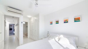A bedroom with a bed, white walls, a ceiling fan, and a hallway leading to a bathroom. - Holiday Home "Casa Minuni" with Sea View, Terrace, Balcony, A/C & Wi-Fi (Almería)