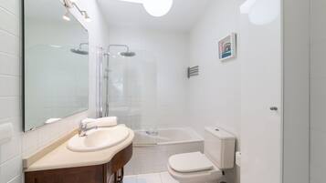 A modern bathroom with a sink, mirror, shower, and toilet.