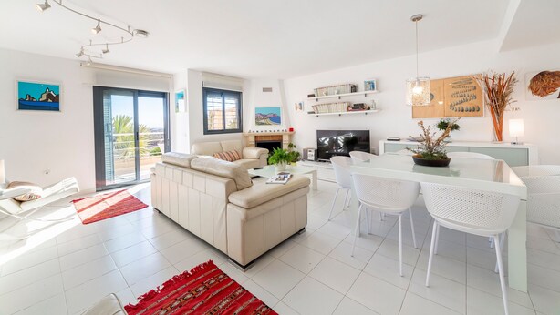 A modern living room with a sofa, dining table, chairs, and a TV. - Holiday Home "Casa Minuni" with Sea View, Terrace, Balcony, A/C & Wi-Fi (Almería)