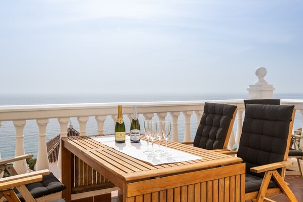A wooden table with two bottles and four glasses on a balcony with a view of the sea. - Villa 'Exclusive - Great Sea View' with Sea View, Wi-Fi and Air Conditioning (Nerja)
