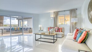 A spacious living area with a glass door leading to an outdoor patio, a central coffee table, and a sofa with colorful cushions. - Villa Ginevra, perfect for large groups, with Pool, Sauna & Garden (Arona)