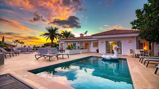 A swimming pool with lounge chairs and a swan float, surrounded by a patio with a building in the background. - Villa Ginevra, perfect for large groups, with Pool, Sauna & Garden (Arona)