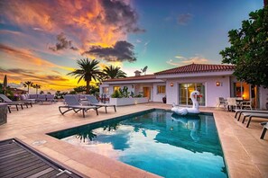 A swimming pool with lounge chairs and a swan float, surrounded by a patio with a building in the background. - Villa Ginevra, perfect for large groups, with Pool, Sauna & Garden (Arona)