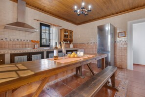 A kitchen with a wooden table, bench, stainless steel appliances, and a tiled backsplash. - Holiday Home "Villa Antonia" with Pool, Wi-Fi, Terraces and Garden (Betancuria)
