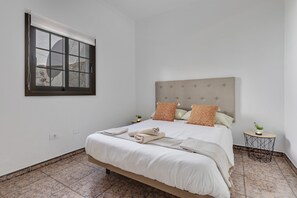 A neatly made bed with a headboard, a small bedside table with a plant, and a window with blinds. - Holiday Home "Villa Antonia" with Pool, Wi-Fi, Terraces and Garden (Betancuria)