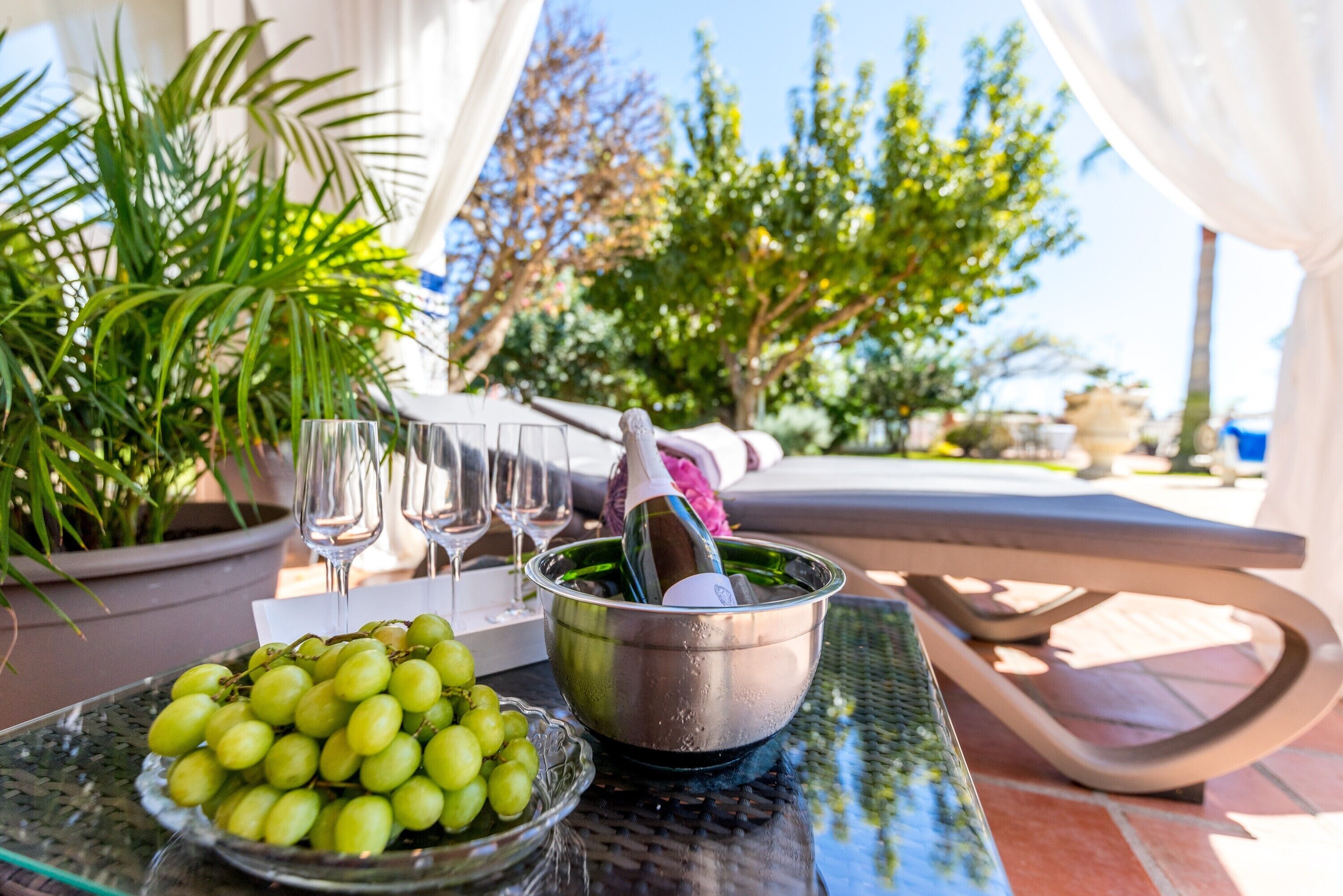 Una mesa con un bol de uvas verdes, una botella de champán y dos copas.
