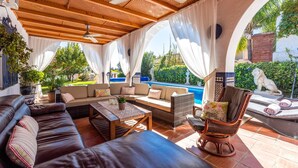 An outdoor patio area with a pool, leather sofas, wicker furniture, and a ceiling fan. - Villa 'El Coto' close to Fuengirola  (Mijas Costa)