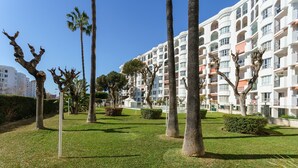 Un edificio residencial con varios balcones, un césped bien cuidado y varias palmeras.