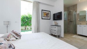 A bedroom with a large bed, a TV, a dresser, and a shower area. - Luxury Villa in Juan-les-Pins (Juan-les-Pins)