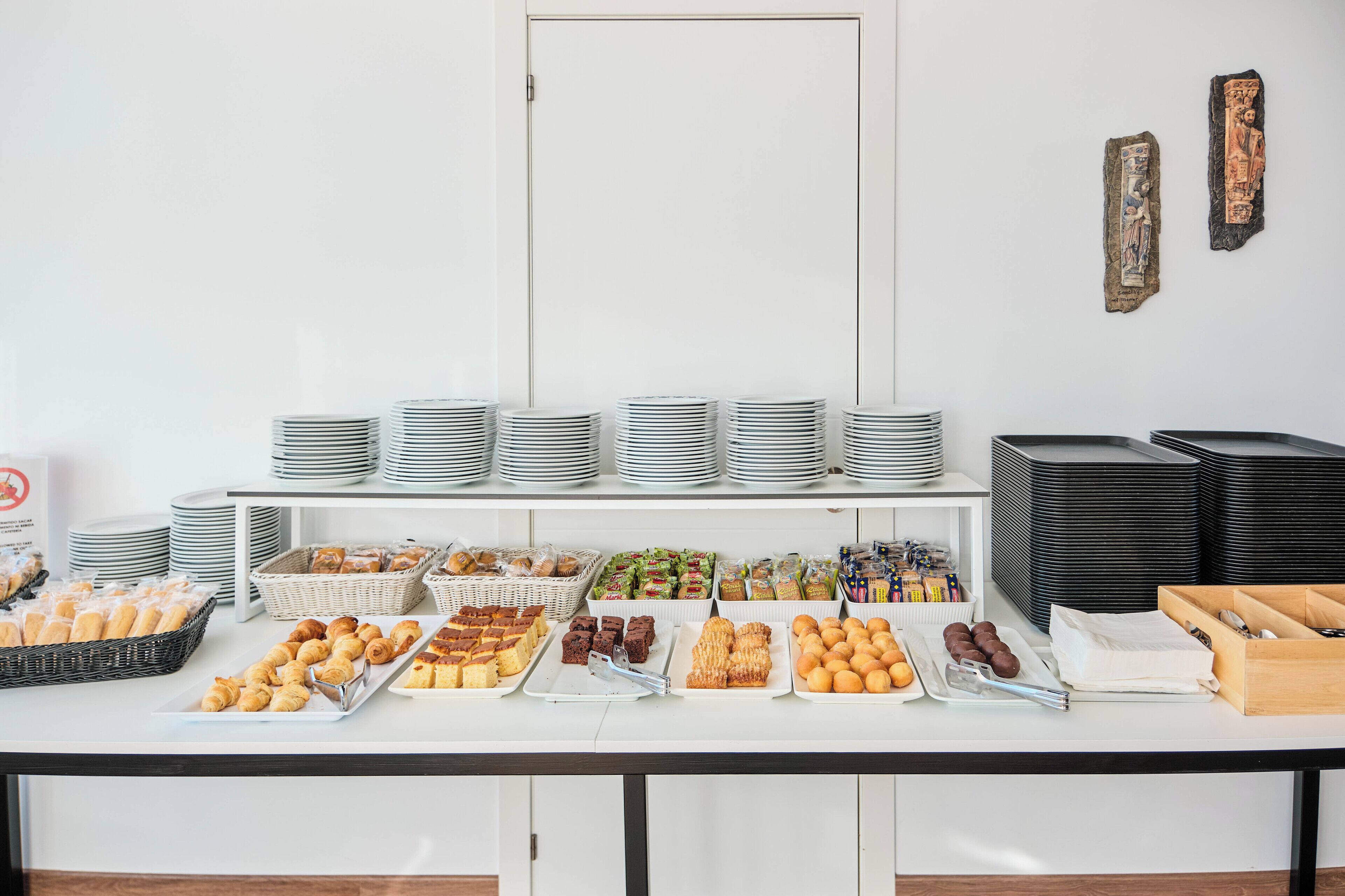 Una mesa de buffet con diversos alimentos y platos apilados.