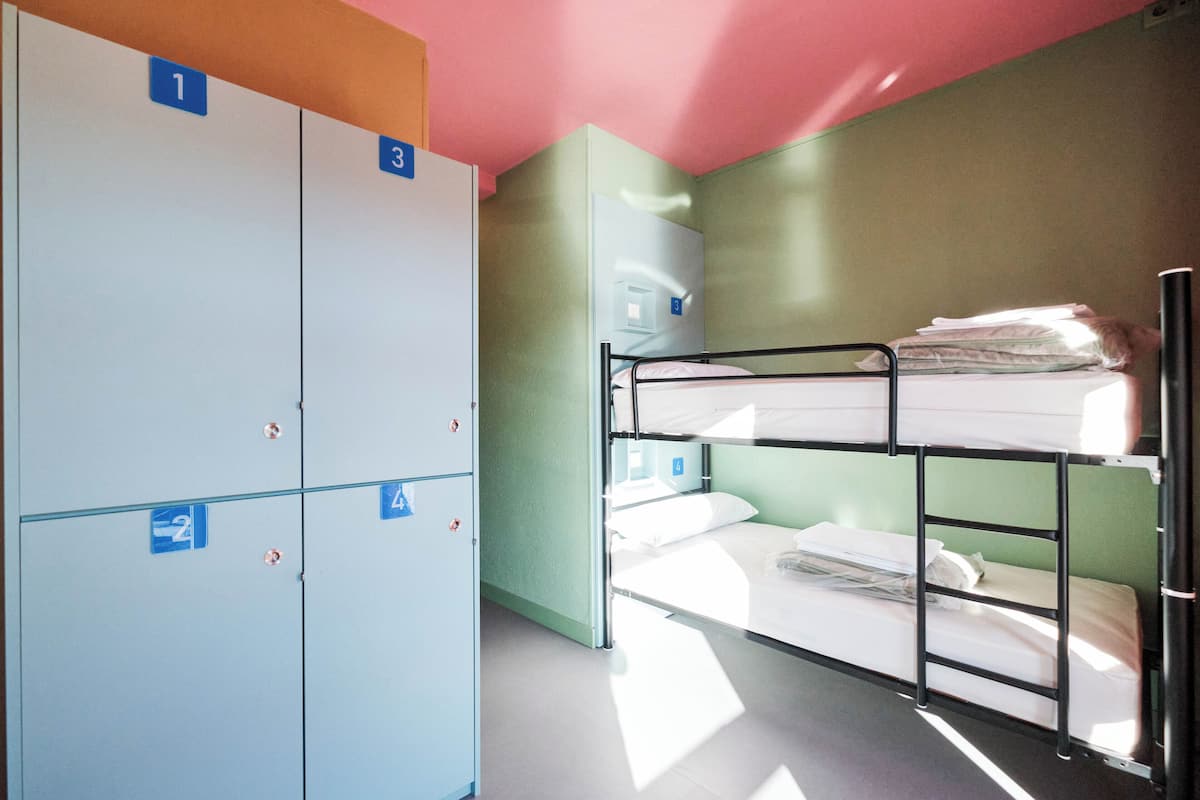 A dormitory room with bunk beds, a wardrobe, and a small desk.