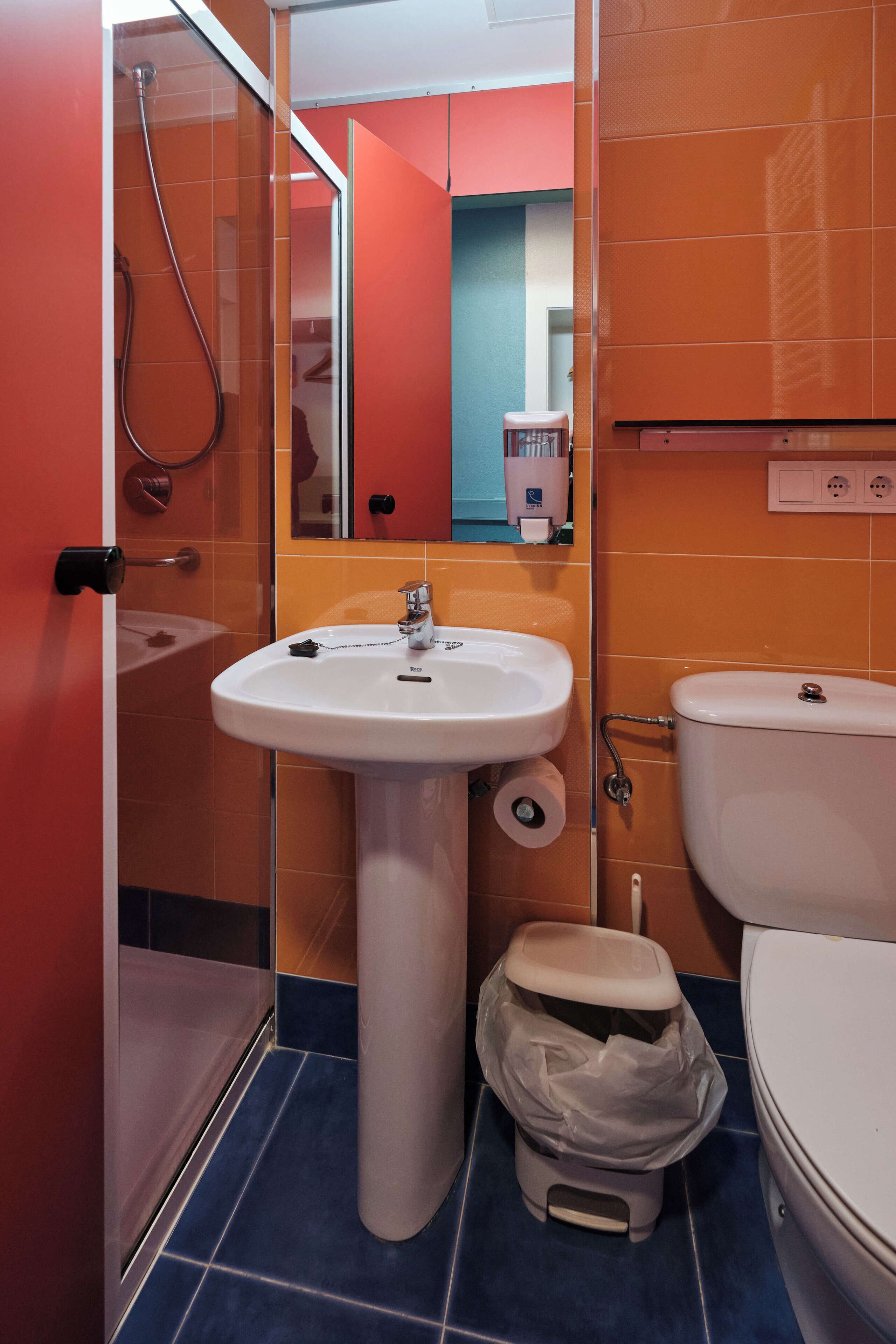 Un baño con lavamanos blanco, inodoro y zona de ducha.