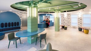 Un interior moderno con techo verde, asientos azules y una zona de recepción.