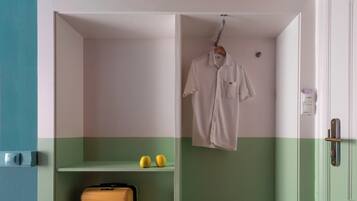 Une pièce aux couleurs vert et blanc, une valise, une paire de chaussures et un vêtement suspendu.