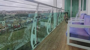 Un balcón con barandilla de vidrio que da a una vista panorámica de la ciudad.