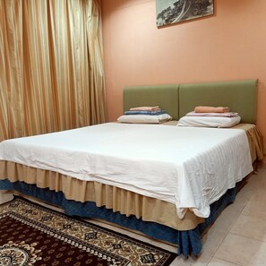 A bed with a white bedspread, green headboard, and a patterned rug. - OYO Home 90352 Muan's Homestay (Kota Belud)