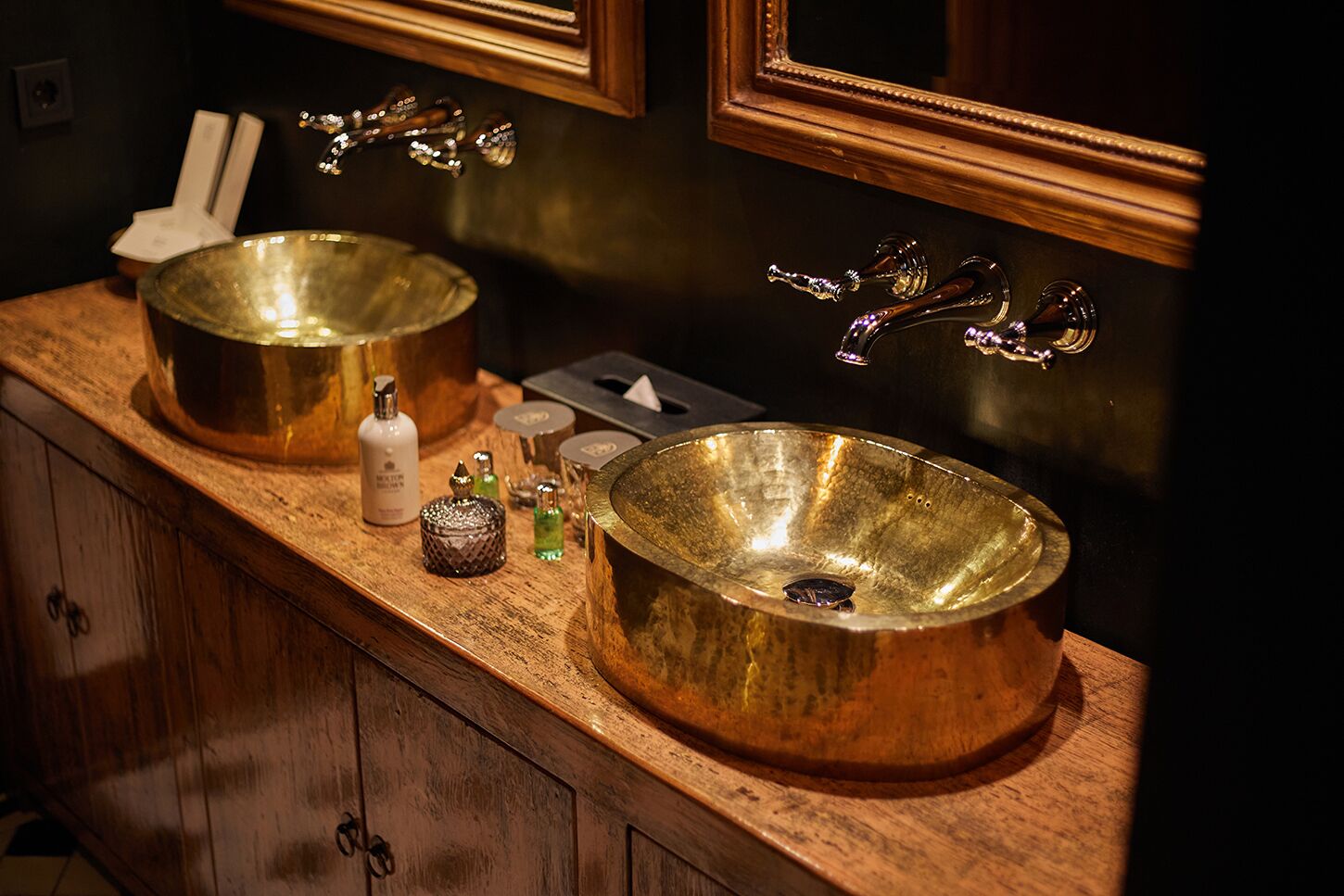 Un baño con dos lavamanos grandes y redondos de metal sobre una encimera de madera.