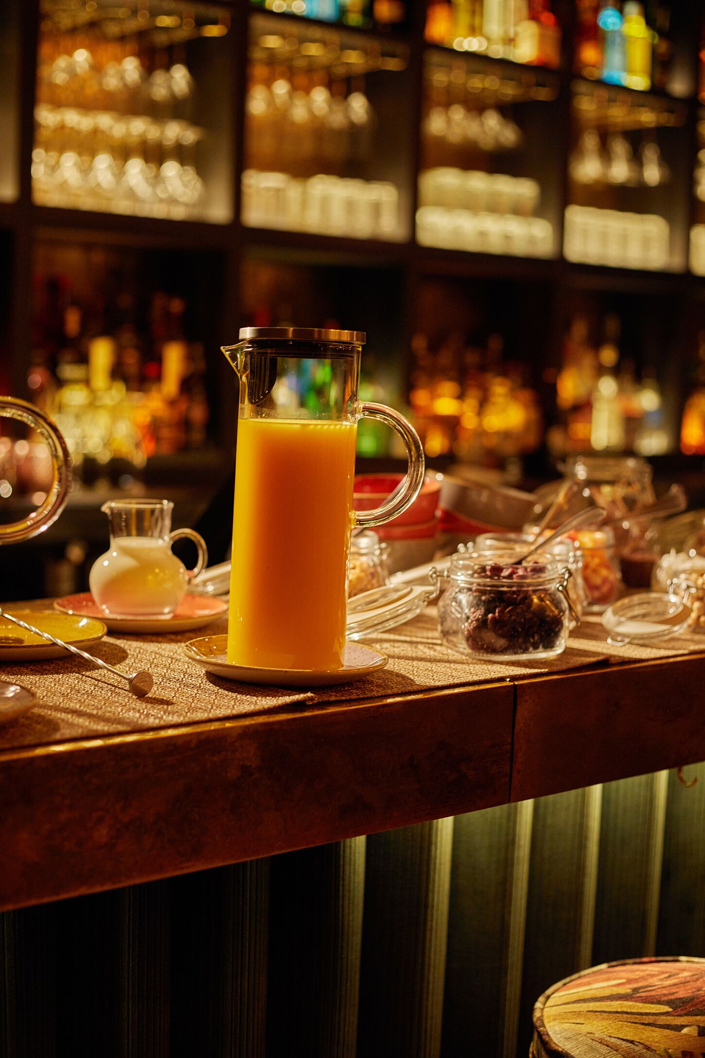 Una barra con una jarra de jugo de naranja, una jarra pequeña y varios frascos de condimentos.