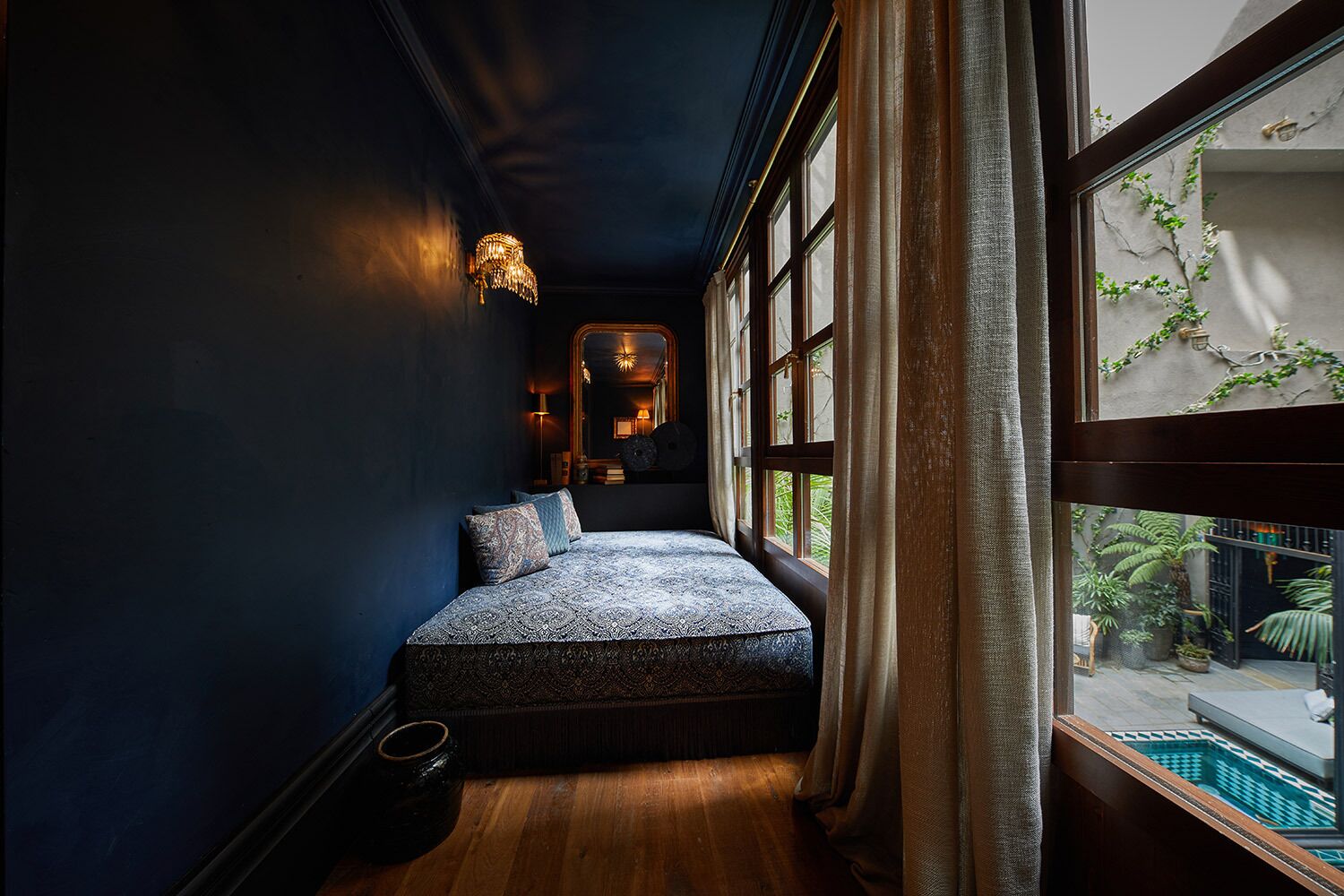 Una habitación pequeña con cama, una ventana grande y vista a una piscina.