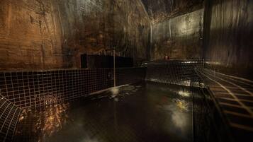 A dimly lit, tiled indoor pool with a single faucet and a small container on the wall.