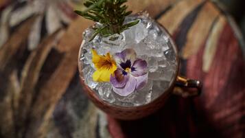 Ein Cocktail mit Eiswürfeln und Blüten auf einer Unterlage.