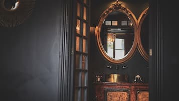 A dimly lit room with a large mirror, a wooden cabinet, and a circular light fixture.