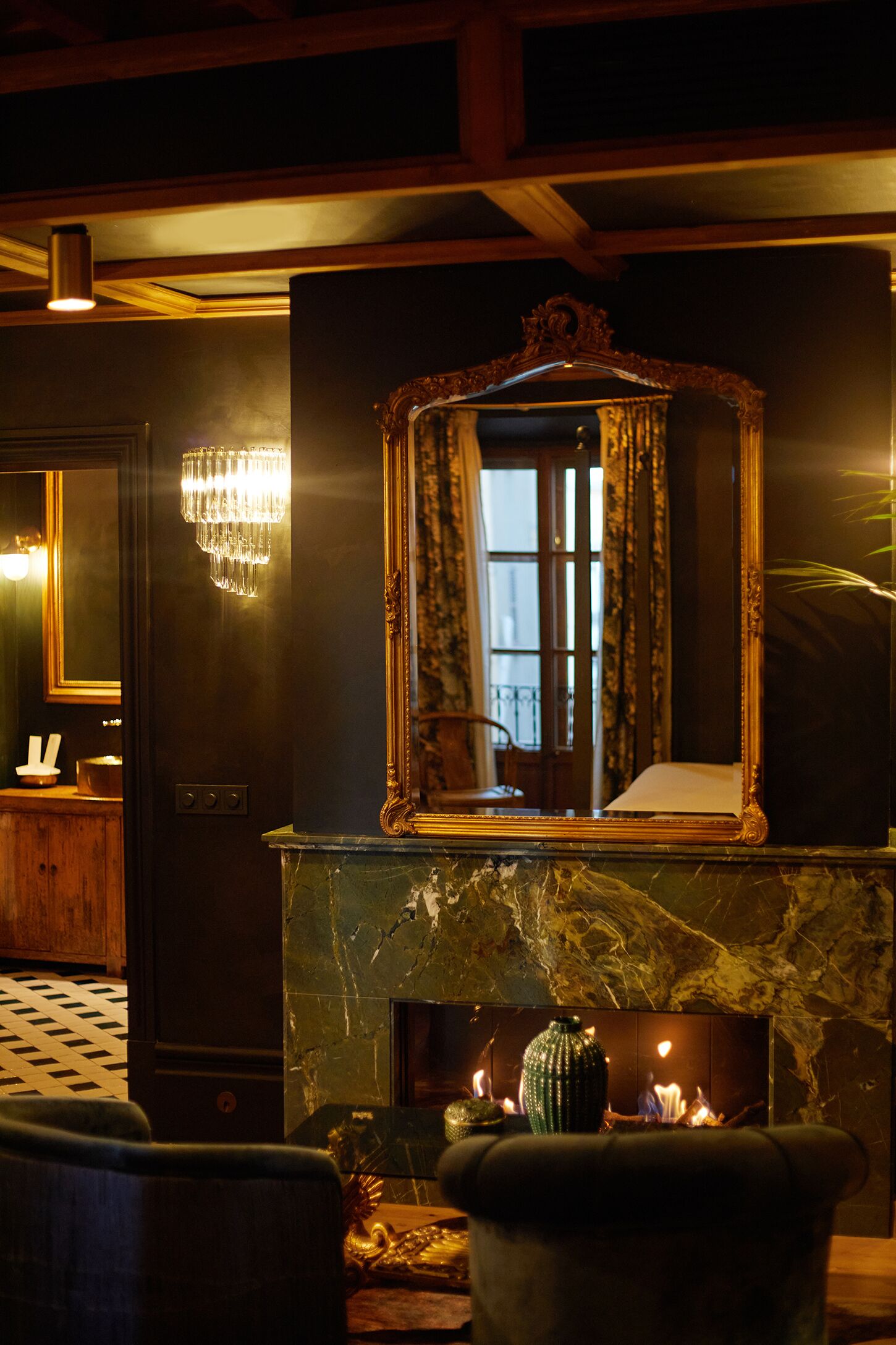Une pièce dotée d’une cheminée en marbre, d’un grand miroir décoratif et d’un lustre.