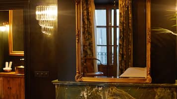 Une pièce dotée d’une cheminée en marbre, d’un grand miroir décoratif et d’un lustre.