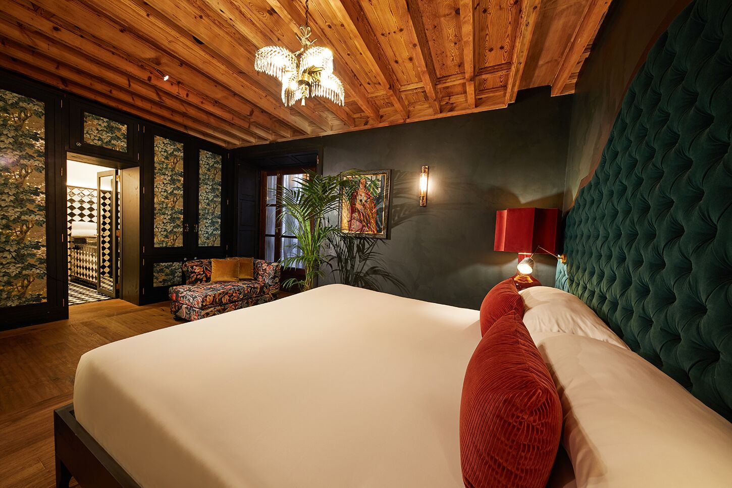 Un dormitorio con una cama grande, techo de madera y vistas a un balcón con plantas.