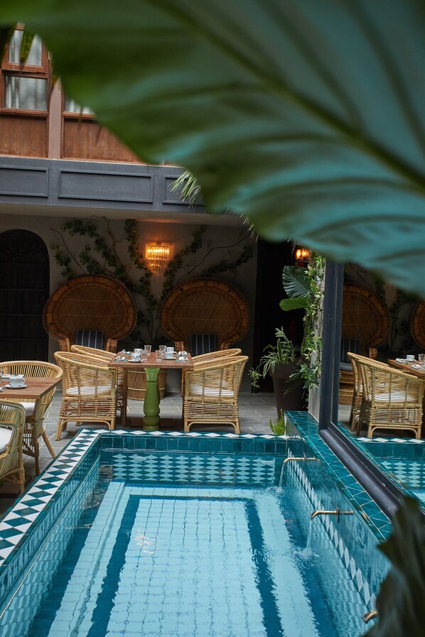 An indoor pool area with wicker furniture and a tiled floor. - Palma Riad (Palma de Mallorca)
