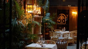 An indoor dining area with wicker chairs, tables set with white tablecloths, and candlelit ambiance. - Palma Riad (Palma de Mallorca)