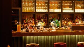 A bar area with shelves of liquor bottles, glasses, and stools.