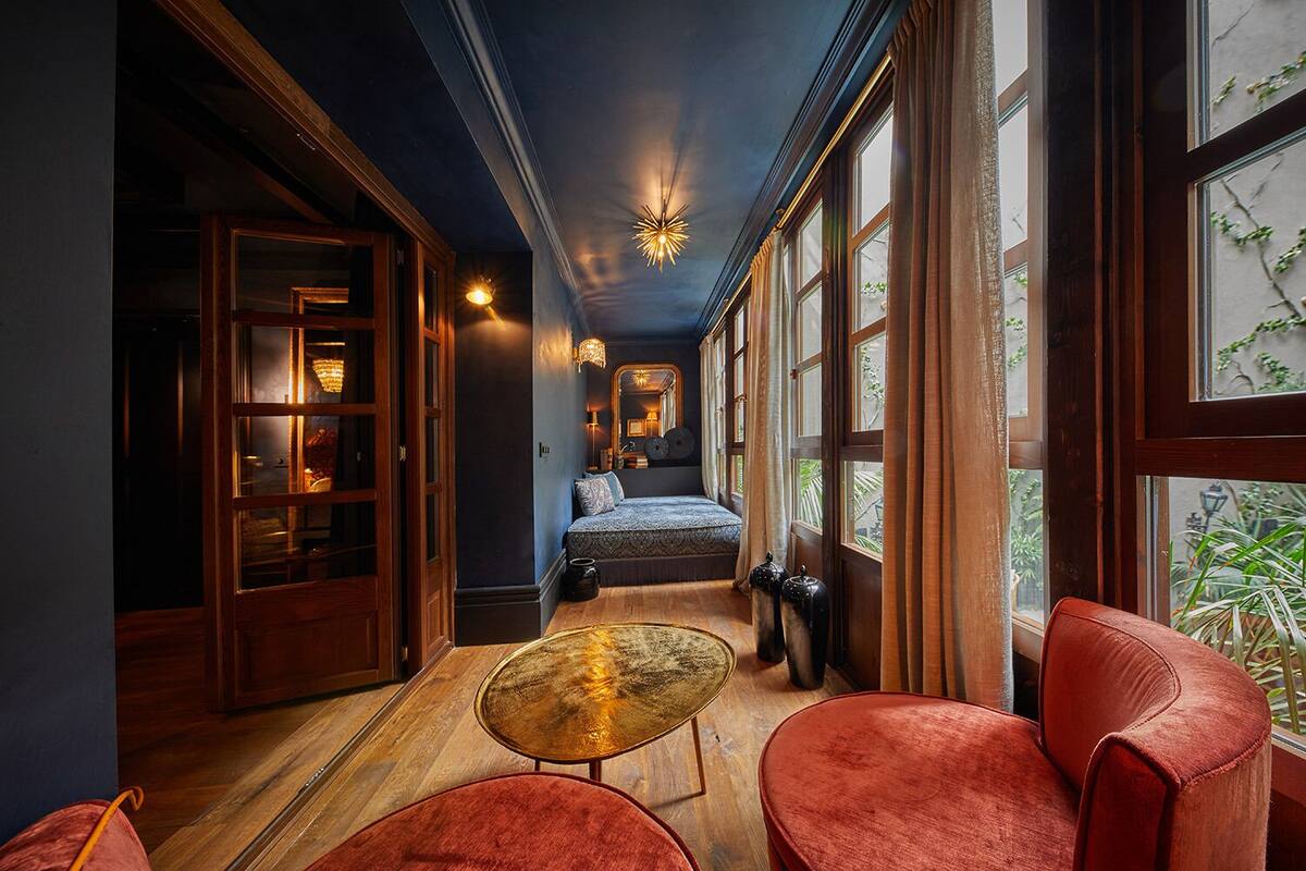 Un couloir avec un lit, une vitrine et une chaise rouge.
