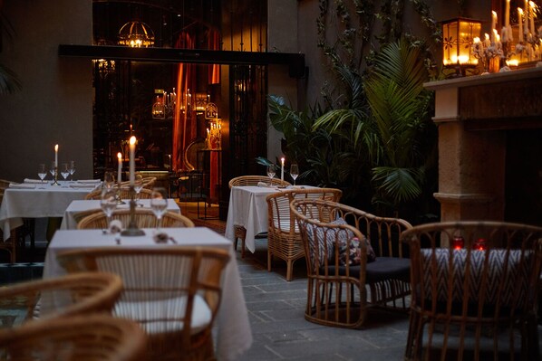 An outdoor dining area with wicker chairs and tables, candles, and ambient lighting. - Palma Riad (Palma de Mallorca)