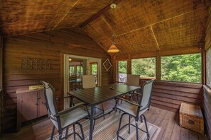 A wooden cabin interior with a dining table, chairs, a small cabinet, and a view of the outdoors. - Dog Friendly Getaway w/ Fire Pit & Game Room (Oakland)