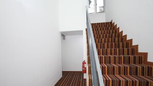 A staircase with striped carpet and wooden steps. - OYO 90345 TM Hotel (Taman Melawati)
